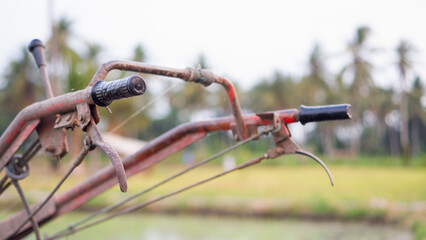 Steering of rice field tractor machine on watery agricultural land in the countryside in Indonesia.