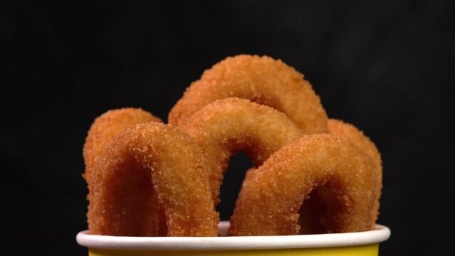 Crisp fried onion rings in coating on dark surface. Perfect for fast food marketing, snack promotions, streetside cafe, retail exhibit, mobile vending