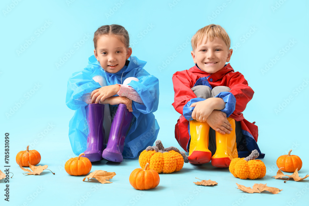 Sticker little children in rubber boots with pumpkins and autumn leaves on blue background