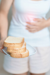 Gluten intolerance, Gluten free and celiac disease or wheat allergy concept. woman hold Bread and having abdominal pain after eat gluten. stomach ache, Nausea, Bloating, Gas, Diarrhea and Skin rash - obrazy, fototapety, plakaty