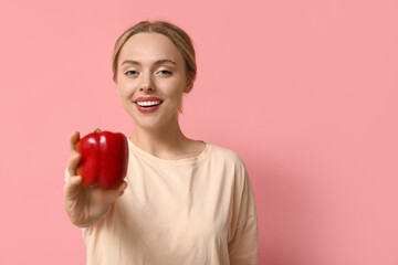 Young woman with bell pepper on pink background, closeup