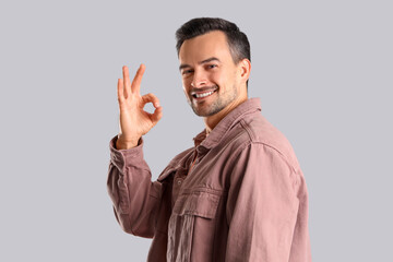 Handsome man showing OK on light background