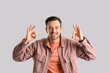 Handsome man showing OK on light background