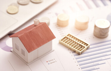 Coins, abacuses, and small houses placed on data sheets