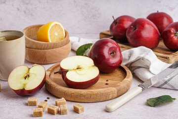 Wooden plate of fresh red apples and bowl with lemon on white background