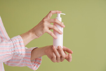 Woman holding bottle of cream against green background