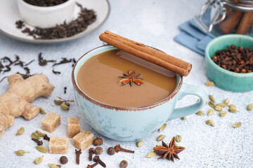 Cup of delicious masala tea with different spices on light background, closeup