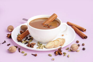 Cup of tasty masala tea with different spices on purple background