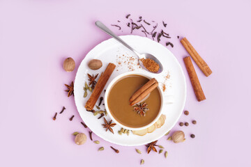Cup of tasty masala tea with different spices on purple background
