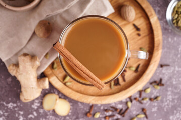 Glass cup of tasty masala tea with different spices on grunge background, closeup