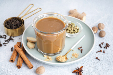 Glass of tasty masala tea with different spices on light background, closeup