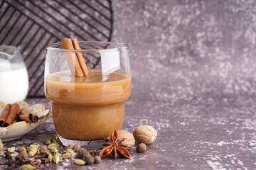 Glass of tasty masala tea with different spices on grunge background, closeup