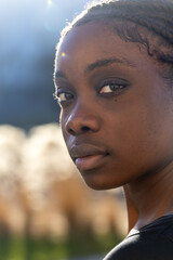 This close-up portrait features a serene African woman with sunlight softly illuminating her face...