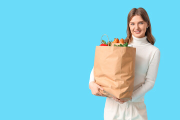 Young woman with full shopping bag on blue background