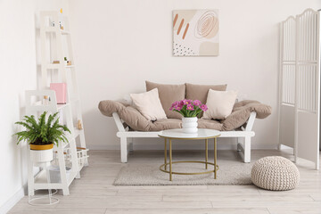 Interior of light living room with couch and tulips on table