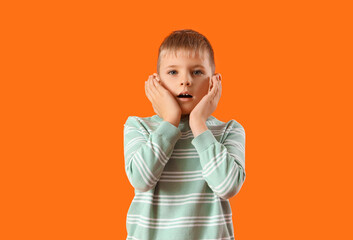 Shocked little boy on orange background