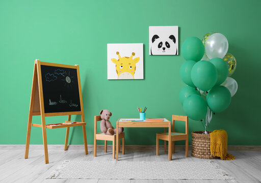 Interior of children's room with bunch of balloons, chalkboard and paintings