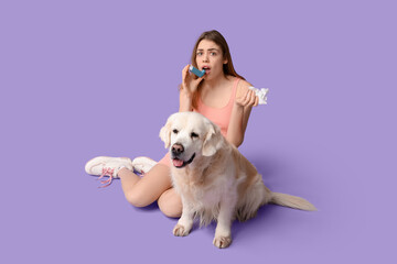 Young woman suffering from pet allergy with labrador dog on purple background