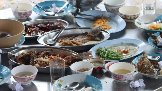 Dirty dishes with leftover food on an oval aluminum table on the porch
