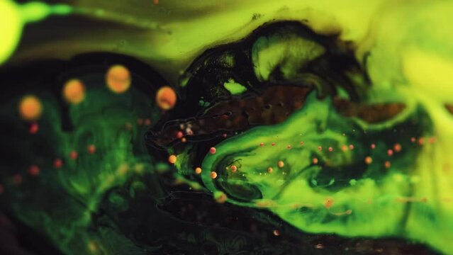 Vertical video. Paint motion background. Mysterious blend. Black neon green liquid ink spreading mix with gold bokeh glitter in captivating hypnotic texture abstract art.