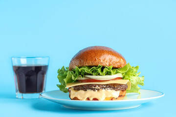 Plate with tasty burger and glass of cola on blue background