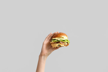Female hand with tasty burger on white background