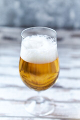 Glass of beer on bright wooden background. Copy space