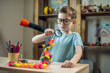 A child boy in the children's room is playing with a toy constructor for teaching the science of chemistry. Assembling molecules from elements. Children's scientific education - 785857672
