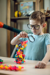 A child boy in the children's room is playing with a toy constructor for teaching the science of chemistry. Assembling molecules from elements. Children's scientific education - 785857849
