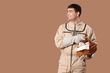 Male beekeeper with basket of honey on brown background