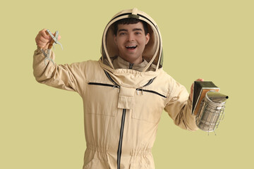 Male beekeeper with supplies on green background