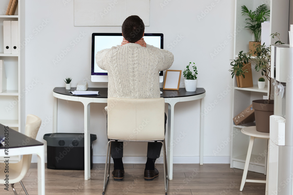 Poster Young businessman suffering from neck pain at table in office, back view