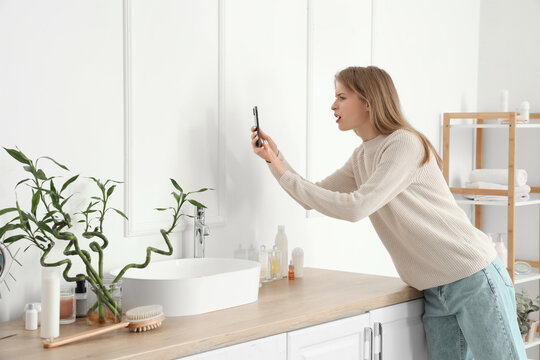 Young woman taking picture of mold on wall in bathroom