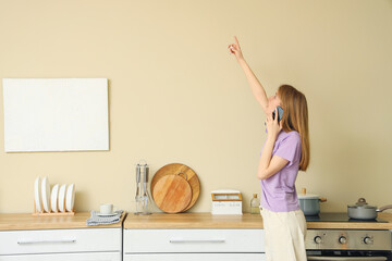 Young woman with mold on wall talking by mobile phone in kitchen