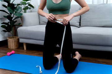 young woman wearing exercise clothes taking a waist measurement