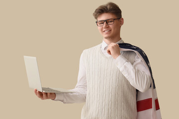 Male programmer with USA flag and laptop on beige background