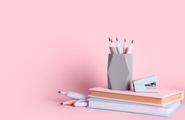 Pencil holder with felt-tip pens and book on pink background