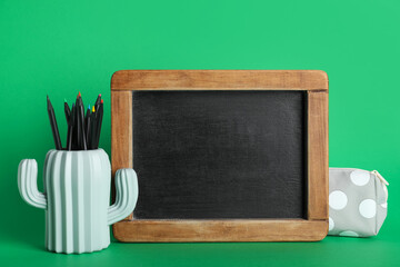 Pencil holder with pencils and blackboard on green background