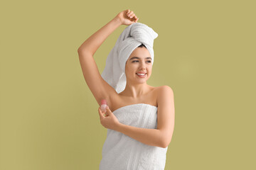 Happy smiling young woman in towel using crystal deodorant on green background