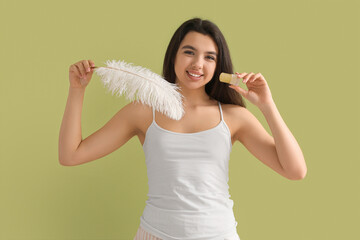 Happy smiling young woman with crystal deodorant and feather on green background