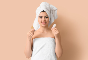 Happy smiling young woman in towel with crystal deodorants on beige background