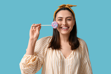 Happy young woman with sweet lollipop on blue background