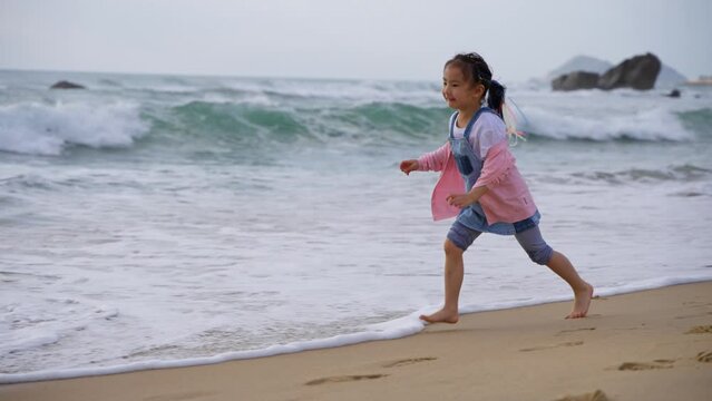 joyful little asian girl running on the beach at Shimei Bay at Wanning Hainan China in slow motion 