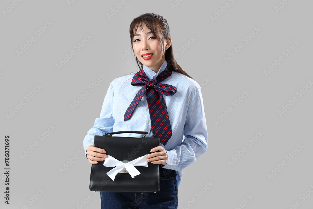 Sticker Stylish young Asian woman with bows and bag on light background