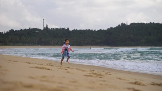 little asian girl running on the beach in slow motion 