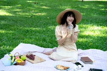 young woman is relaxing on a blanket with food  book  and drinks