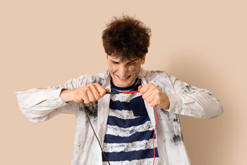 Electrocuted young man with burnt face and wires on beige background