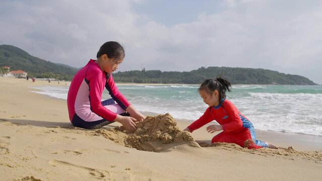 two asian kids playing sand on the beach at Hainan China