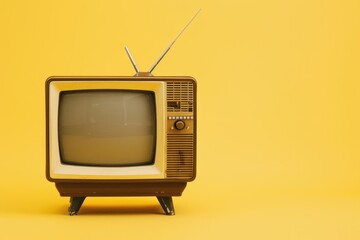 Vintage television set with antenna on a bright yellow background, representing retro technology and entertainment.
