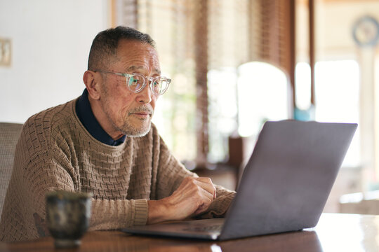 スマホとパソコンで調べ物をする日本人シニア男性
